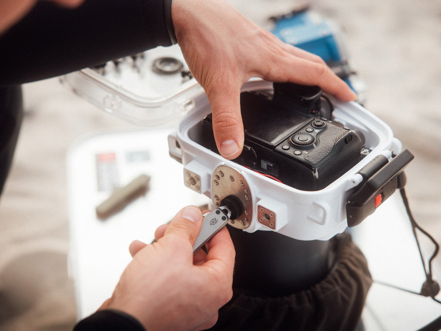 A man using his Elko keychain pocket knife to screw on the water housing of his camera.