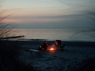 Surfers warming themselves with a bonfire at the beach in Germany.