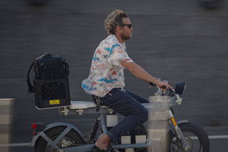 Professional skateboarder and photographer Arto Saari riding an electric bike with his camera gear in tow.