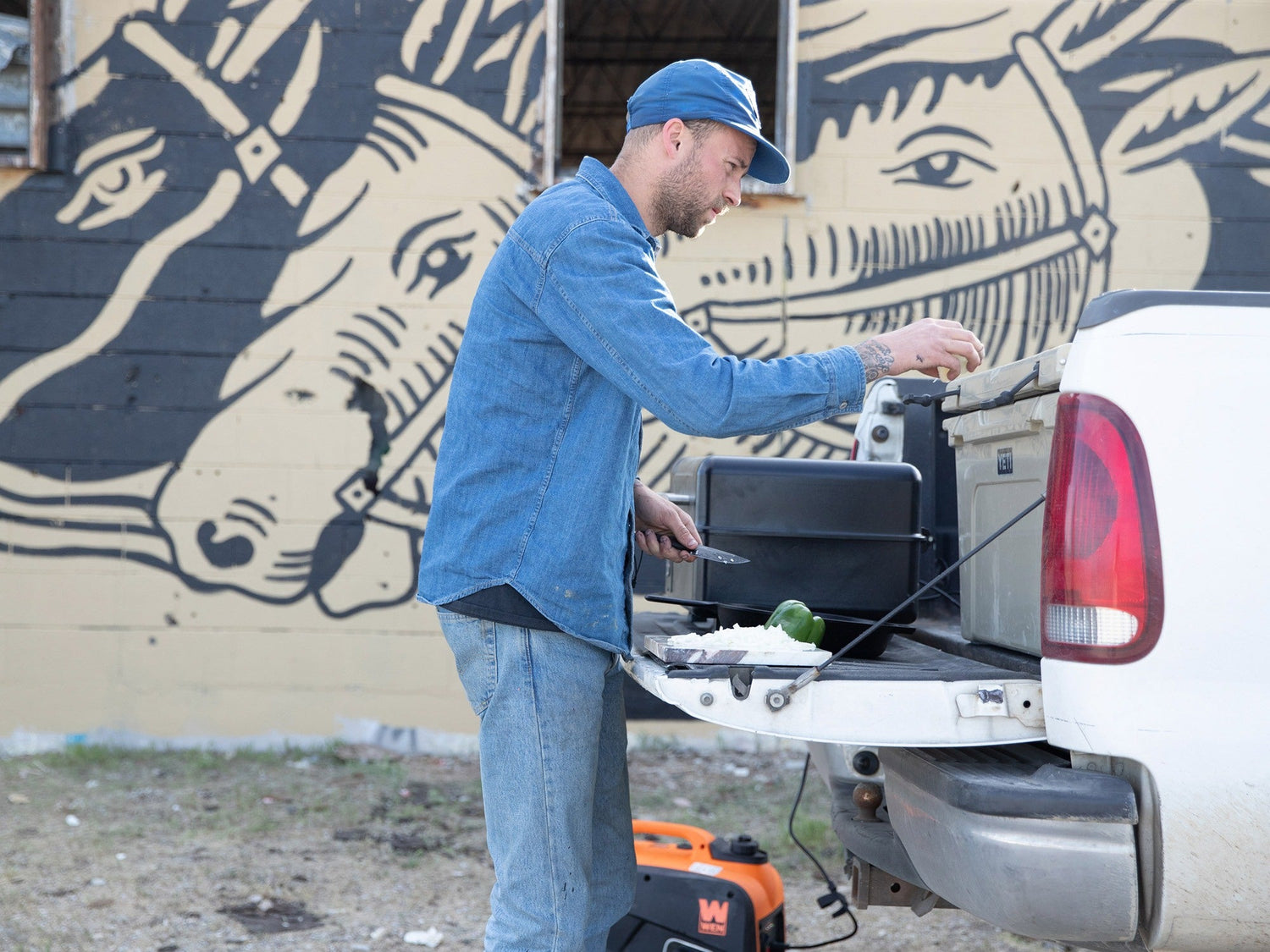 Artist Jess Mudgett preparing dinner with his Hell Gap fixed blade camping knife on a tailgate.