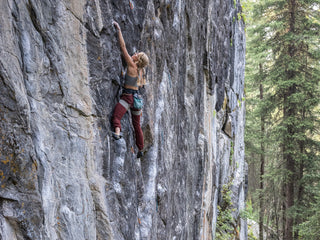 Professional rock climber and photographer Savannah Cummins climbing a vertical face.