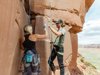 Professional rock climber and photographer Savannah Cummins about to climb a vertical rock face with her boyfriend.