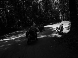 A group of motorcyclist going around a turn on a dirt forest road in Arkansas.