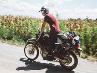 A motorcyclist standing up while riding own a dirt road.