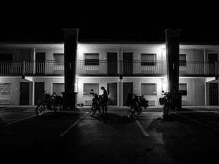 Motorcycles parked in front of a motel at night.