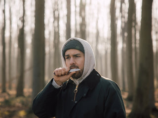 A man eating an apple slice off the blade of his Wayland classic Barlow slip joint folding knife in the Ghost Forest of Germany.