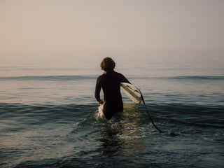 A man walking into the surf in the North Sea, Germany.
