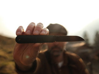 A man holding up the all black Wayland classic Barlow EDC folding slip joint pocket knife. 