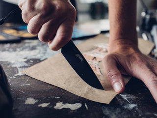 A man cutting paper with the Hell Gap fixed blade camping knife.