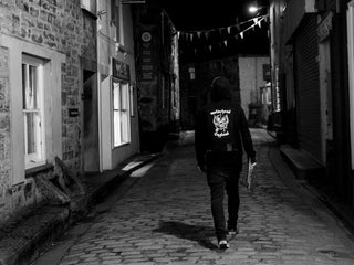 UK artist Schoph Schofield walking down a cobble stone back street in England.