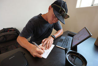 A man taking notes with his Burwell EDC click pen while working on his laptop.