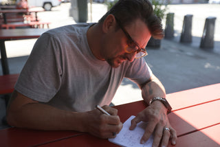 Professional chef Chris Cosetino writing in his notebook with his Stilwell EDC compact travel pen.