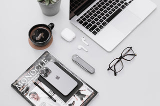The Wells EDC flipper button lock folding pocket knife in raw aluminum on a desk with a apple lap top.