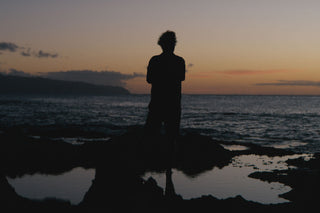 Professional skateboarder and photographer Arto Saari standing on a reef looking out to sea in Hawaii.