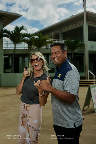 The principals of Kahuku elementary school throwing shakas.