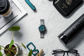 The James x Timex Emerald GMT Automatic titanium watch on a marble surface.