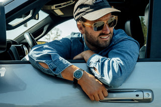 A man hanging out of his truck window wearing the James x Timex GMT Automatic titanium watch.
