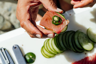 A man holding a piece of sashimi with jalapeno. 