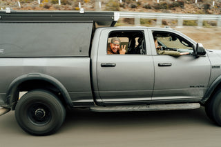 A man flashing the peace sign on from a truck on the road in Baja California.