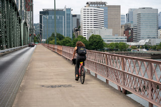 A woman riding her bike across a bridge towards Portland, Oregon.