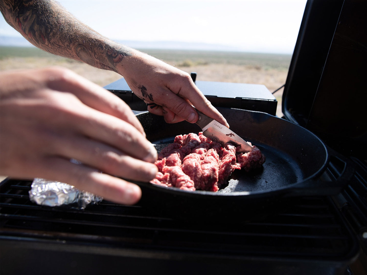 Artist Jess Mudgett cooking food on his tailgate with his Hell Gap fixed blade camping knife. 