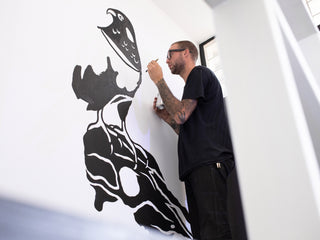 Artist Jess Mudgett painting a mural indoors.