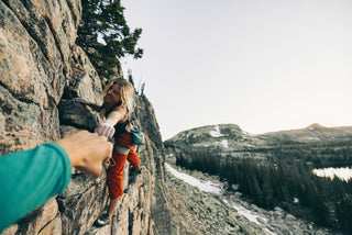 Savannah Cummins giving knucks to her climbing partner on the rock face.