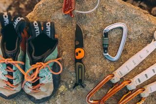 The Redstone pocket knife next to climbing gear on a rock.