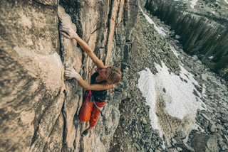 Savannah Cummins climbing up a steep rock face.