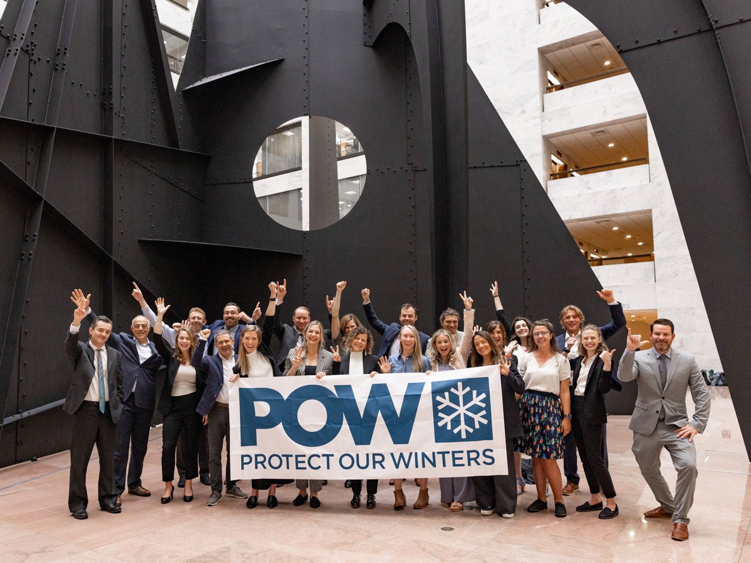 The Protect Our Winters organization holding up a banner with their logo.
