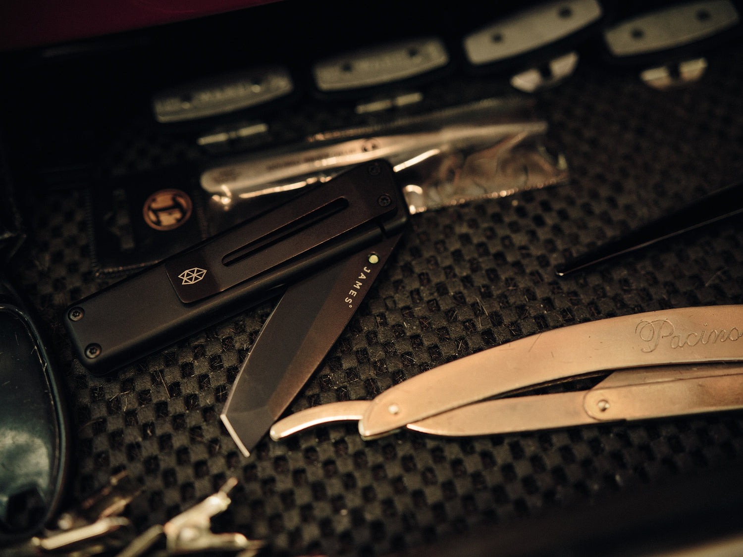 A black Chapter EDC folding frame lock pocket knife next to barber Paul Hewitt's tools. 