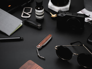 The Pike classic slip joint folding pocket knife on a desk with a camera and other items. 