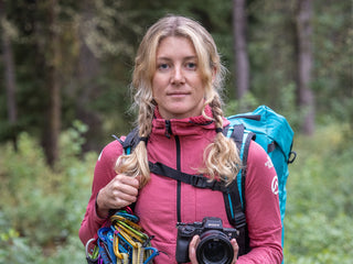 Professional rock climber and photographer Savannah Cummins with her climbing gear in the woods.