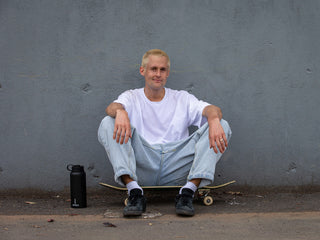 Artist Sebo Walker sitting on his skateboard.