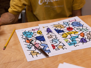 Artist and skateboarder Sebo Walker signing art prints with his James Brand collab knife on the table.