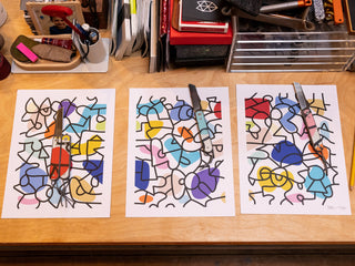 A group of signed prints from artist and skateboarder Sebo Walker with his collab knives on top.