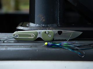 The Redstone EDC serrated folding slide lock pocket knife on a trucks tailgate.